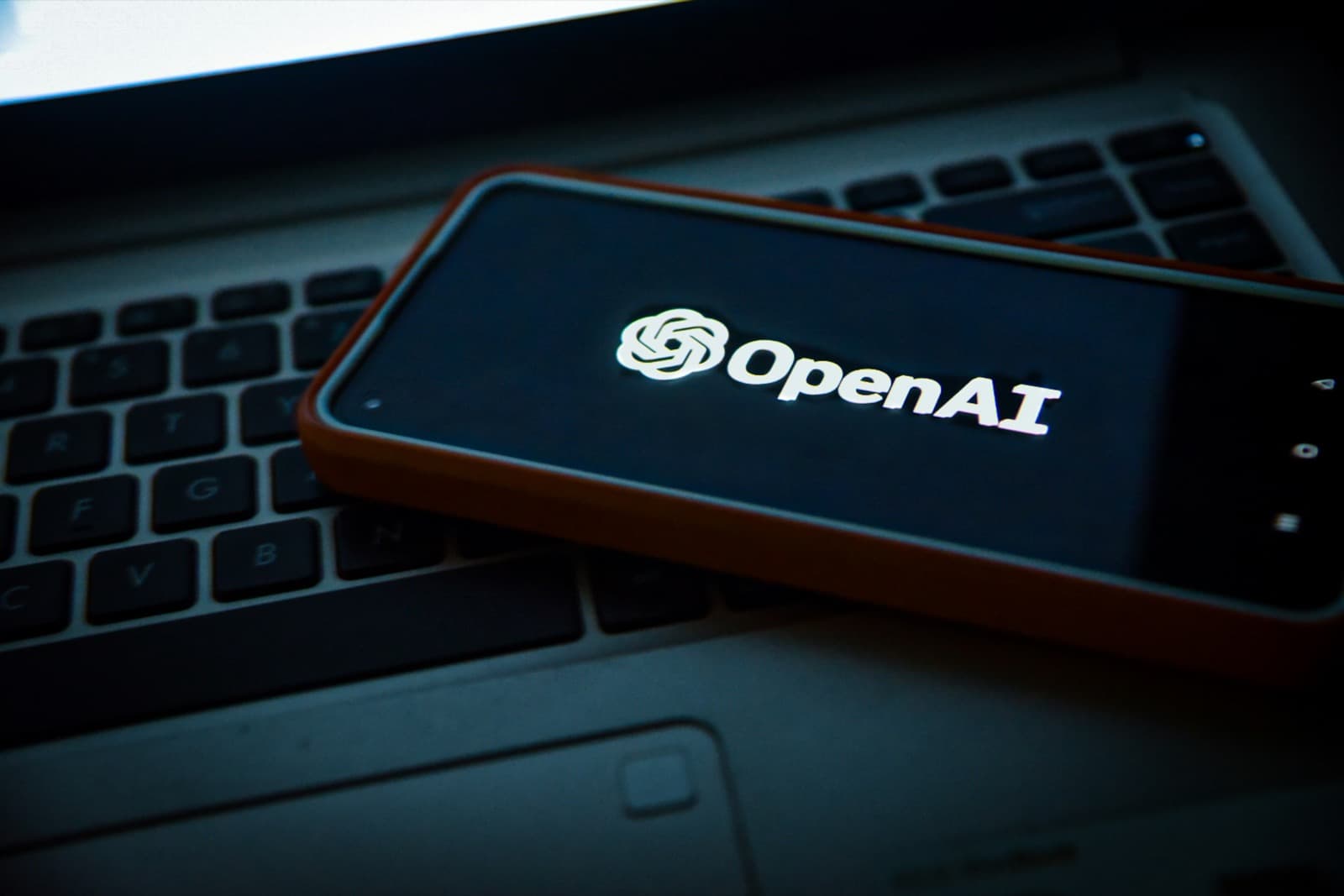 Phone showing OpenAI logo on a laptop keyboard